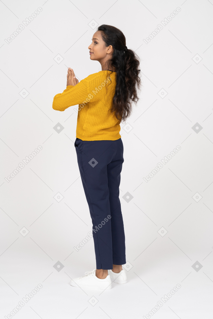一个穿着休闲服的女孩做祈祷手势的侧视图