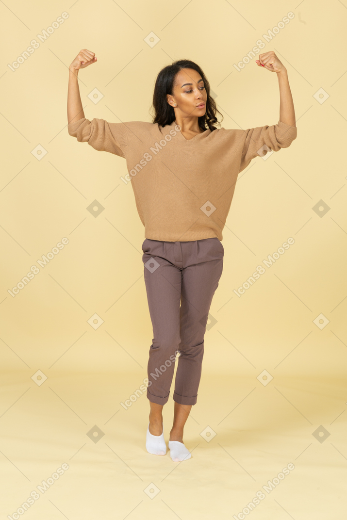 一位黑皮肤的年轻女性，举起手，握紧拳头的前视图
