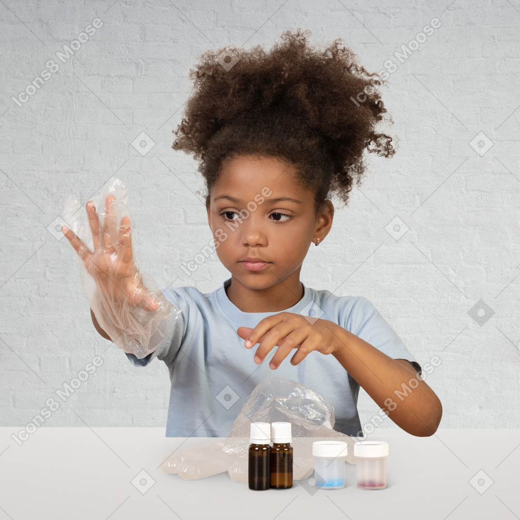 A little girl in gloves standing behind desk with flacons