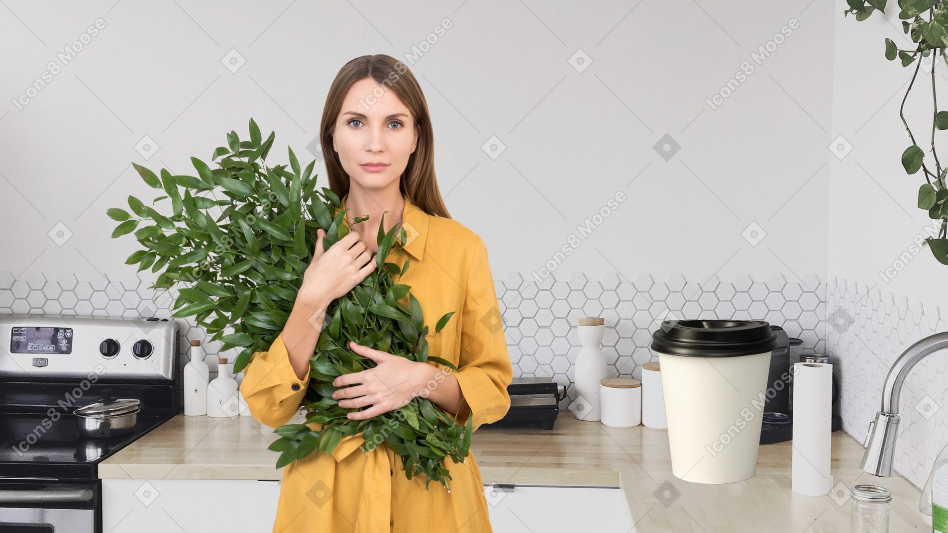 A woman holding a plant in a kitchen