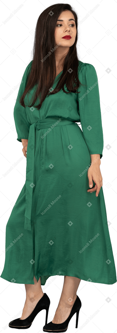 Three-quarter view of a proud young lady in green dress putting hand on hip