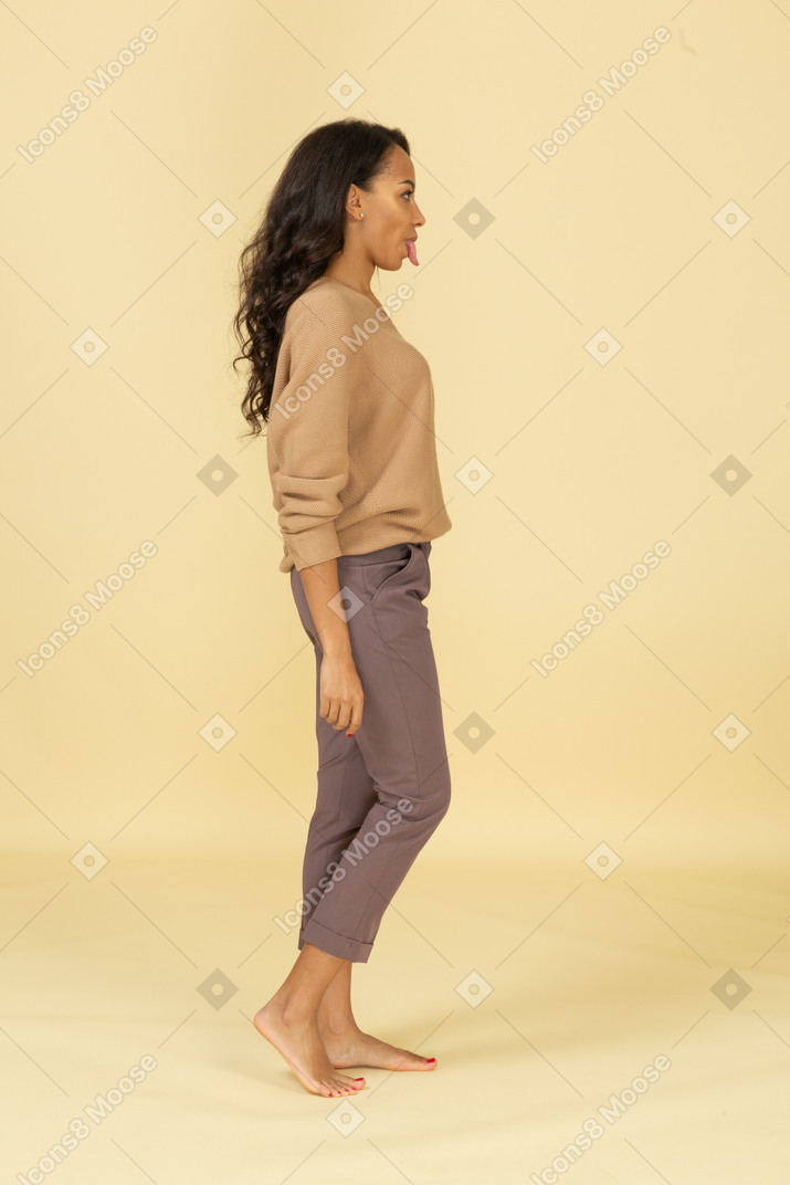Vista laterale di una giovane donna in abiti casual che mostra la lingua