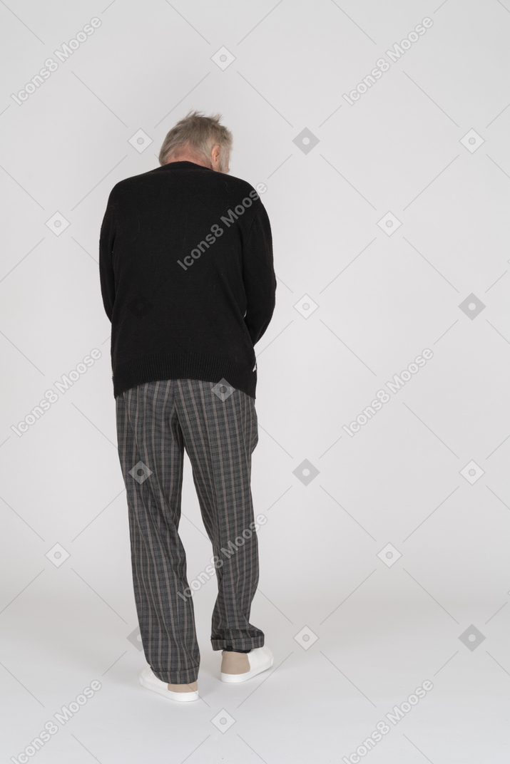Пожилой мужчина стоит спиной к камере