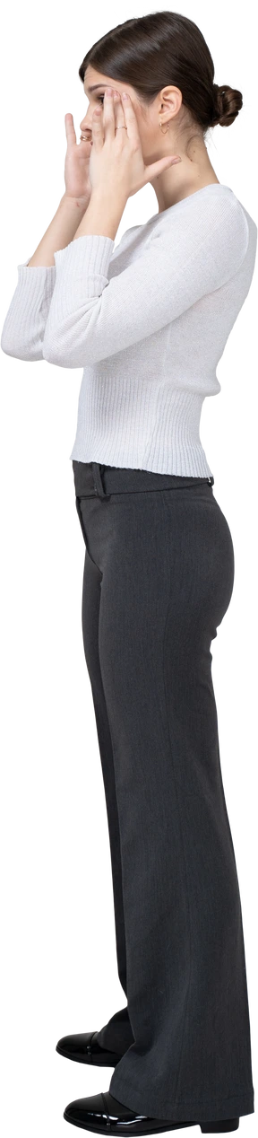Side view of a surprised young woman in office clothing touching face