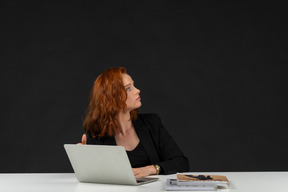 Mujer joven distraída sentada en la computadora portátil