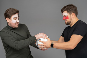 Two male football fans fighting for the ball