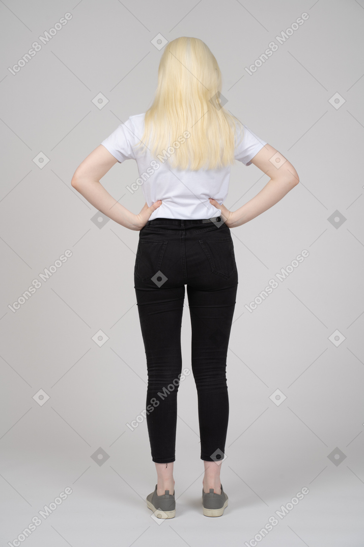 Back view of a blonde girl with her hands on waist