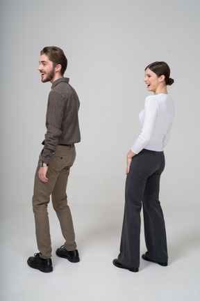 笑对年轻夫妇在办公室服装中的侧视图