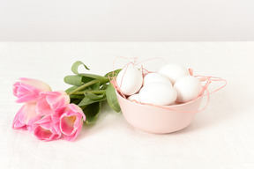 Un bol avec des oeufs et un bouquet de tulipes