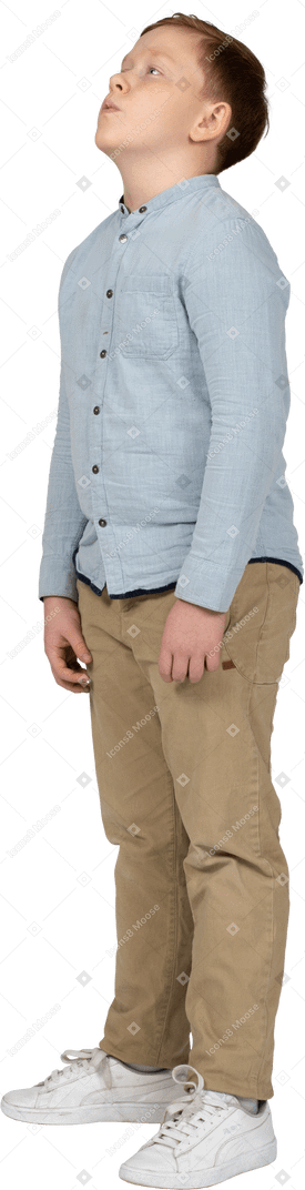 Vista lateral de un niño con ropa informal mirando hacia arriba