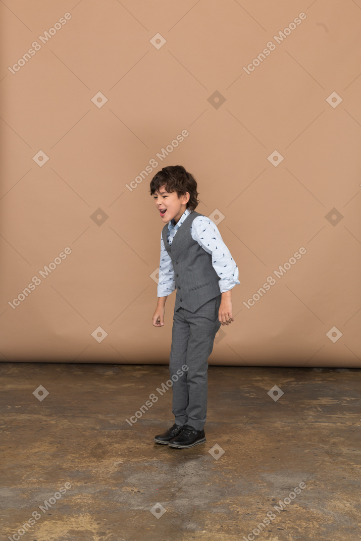 Angry boy in suit standing with clenched fists