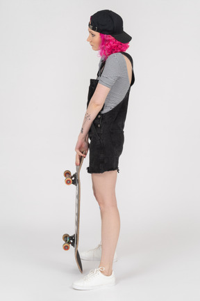 Hunchbacked teenage girl holding a skateboard in profile