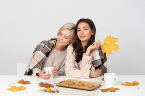 Young women drinking coffee and leaning on each other