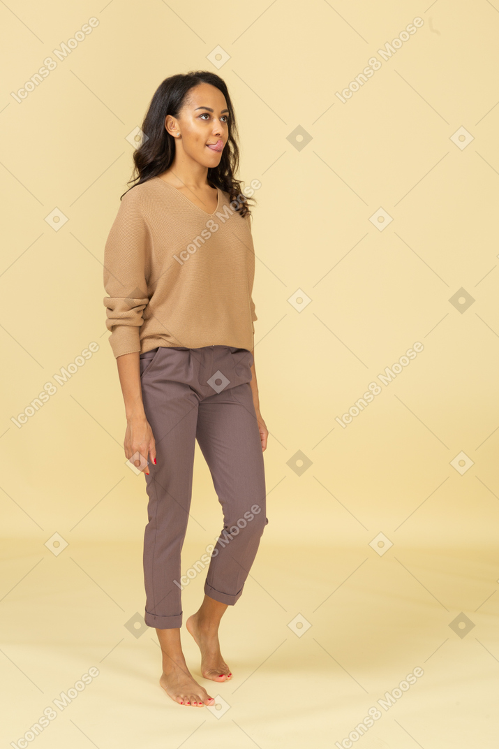 Vista di tre quarti di una giovane donna in abiti casual che mostra la lingua
