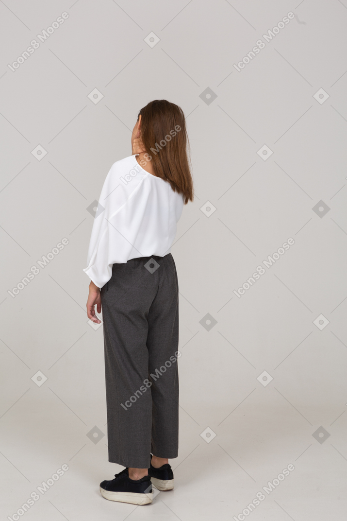 Three-quarter back view of a young lady in office clothing tilting head