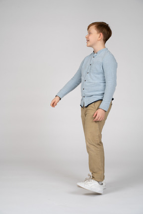 Vista laterale di un ragazzo felice con in piedi con il braccio esteso