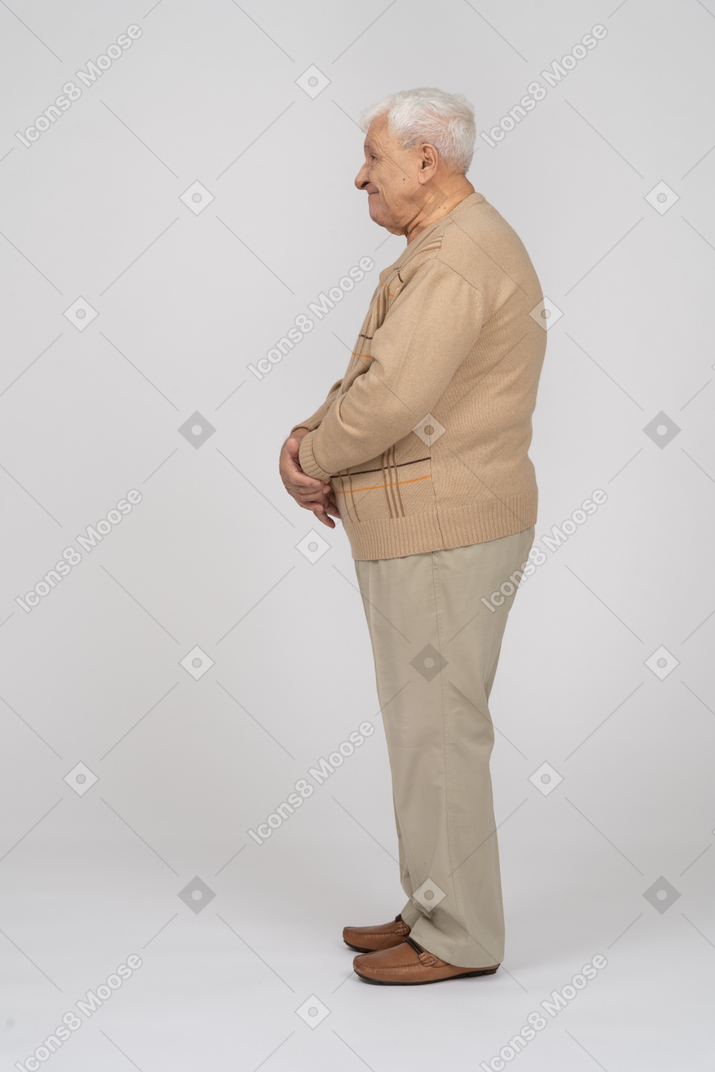 Seitenansicht eines glücklichen alten mannes in freizeitkleidung, der still steht