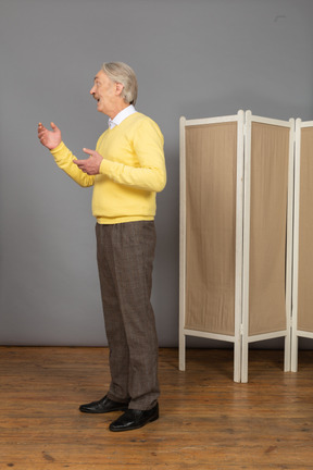 Side view of an old man explaining something while gesticulating