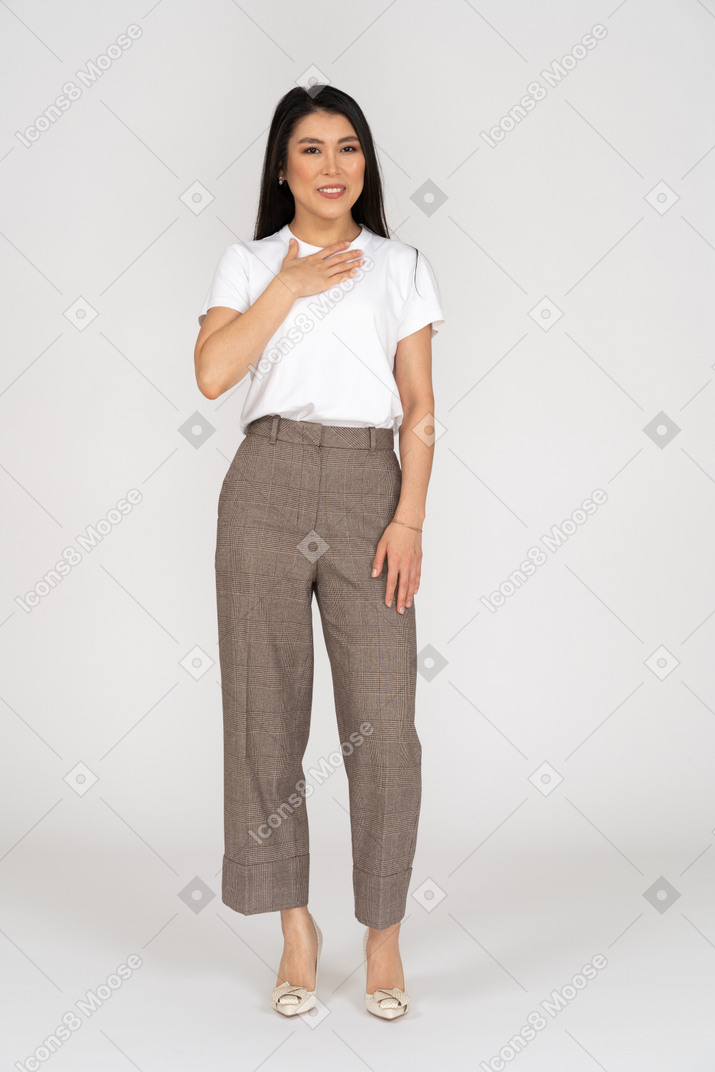 Front view of a pleased young lady in breeches and t-shirt touching her chest