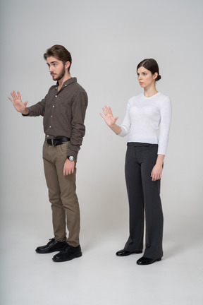 Трехчетвертный вид молодой пары в офисной одежде, протягивающей руку
