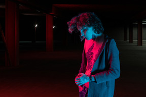 A young man standing in a dark parking garage and smoking