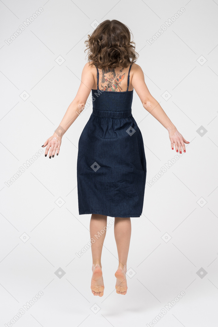 Slim brunette woman levitating back to camera