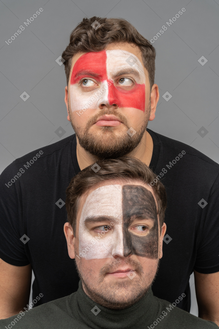 Vista frontale di due tifosi di calcio maschi con arte del viso