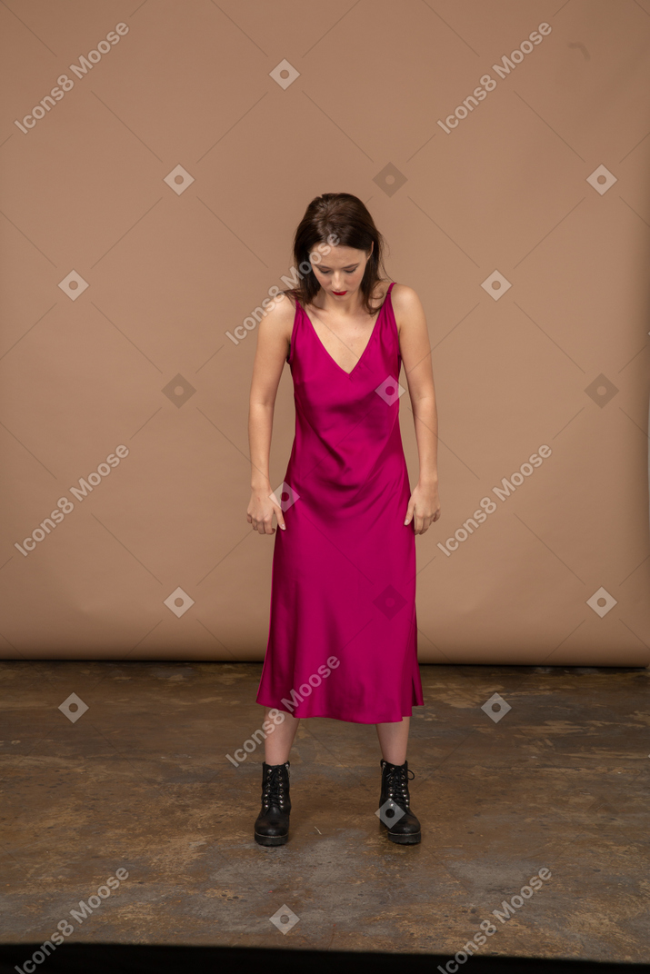 Vue de face d'une jeune femme en belle robe rouge regardant vers le bas