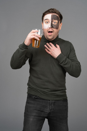 Front view of a surprised male football fan holding a beer