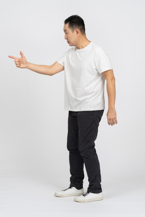 Vista laterale di un uomo in abiti casual che punta a qualcosa con il dito
