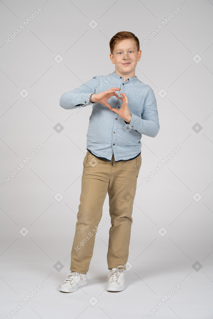 Front view of a boy making heart with fingers and looking at camera
