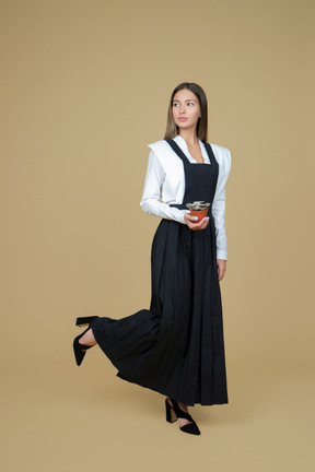 Belle femme en robe longue noire et blanche tenant un pot