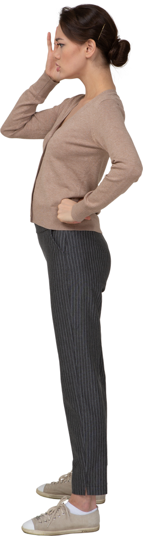 Vista laterale di una giovane donna in pullover e pantaloni che toccano la sua testa