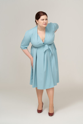 Vista frontale di una donna in abito blu che soffre di dolore nella parte bassa della schiena