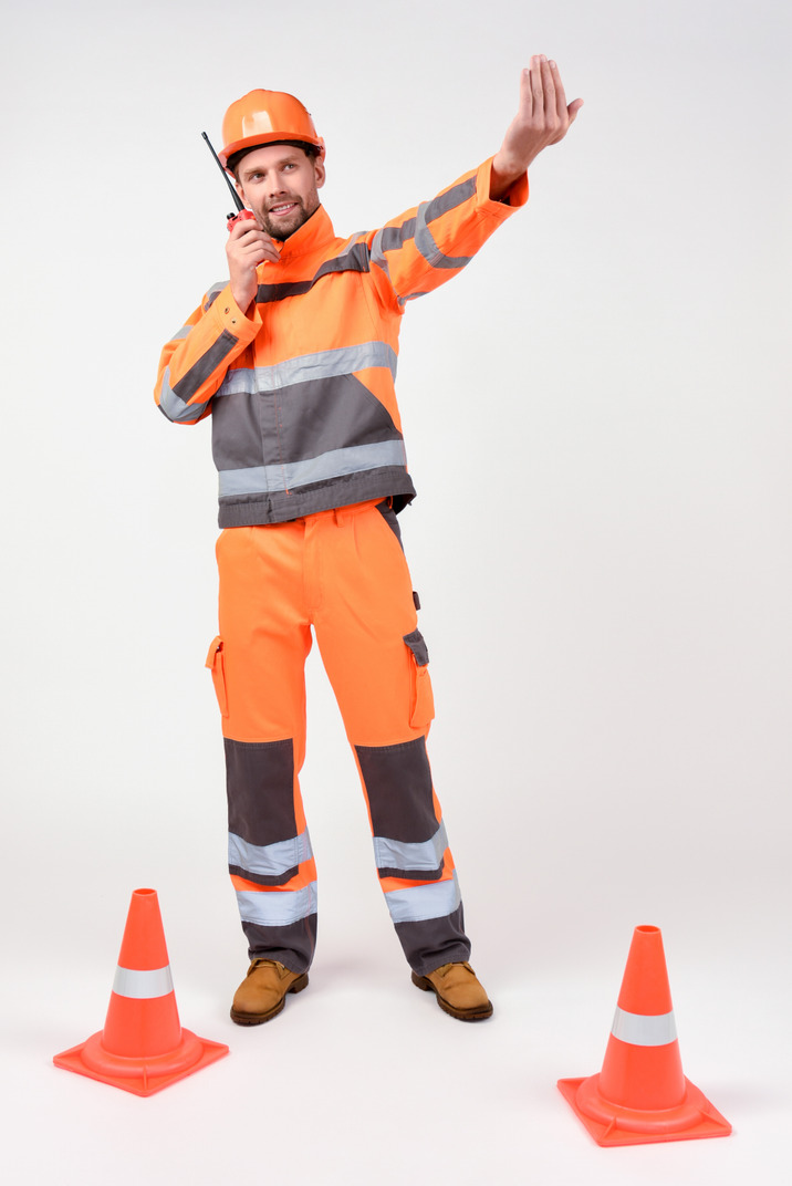 Construction worker using radio phone and showing somewhere