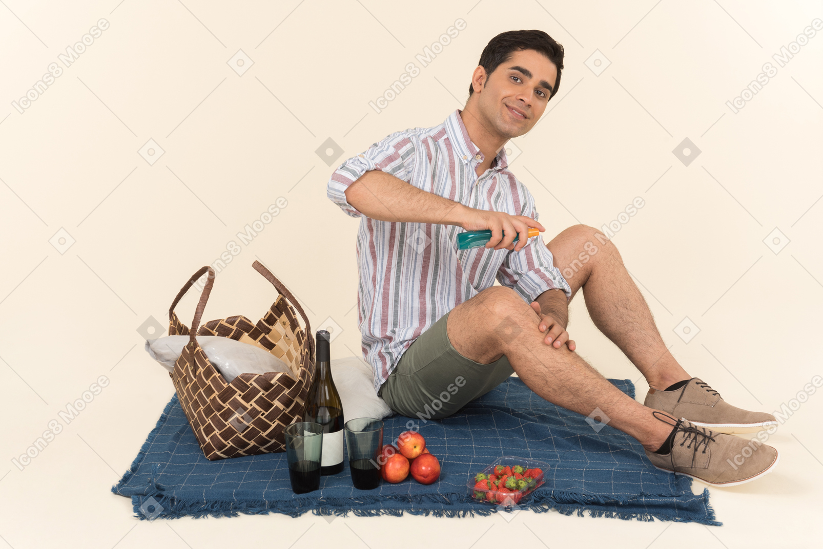 Young caucasian man sitting on blanket andspraying a spray on his leg