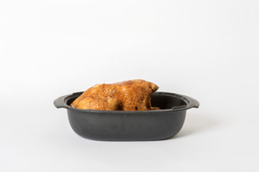 Black oven form with fried chicken in it