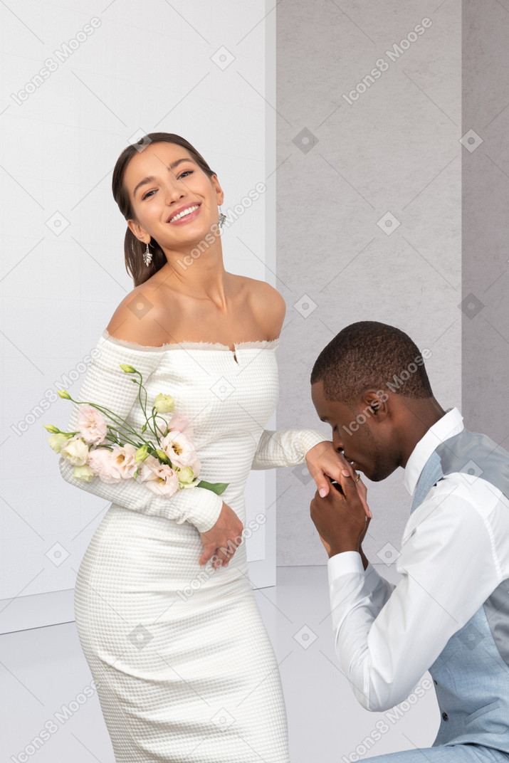 A man kneeling down next to a woman in a white dress