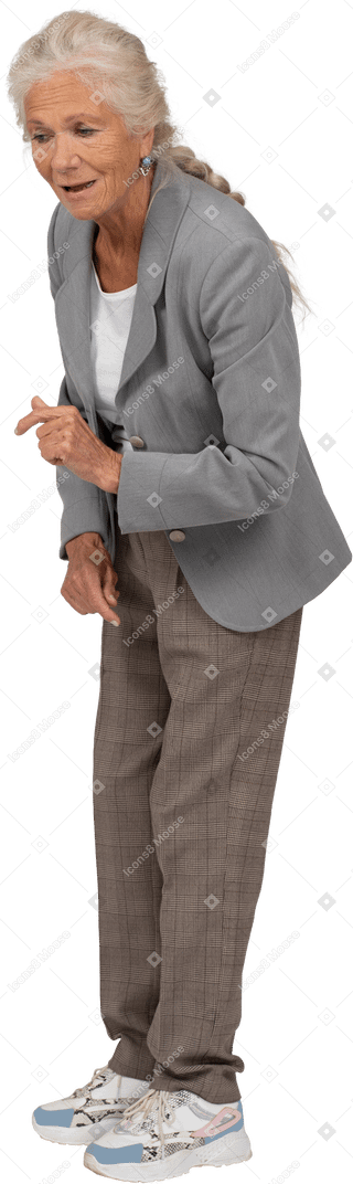 Side view of an old lady in suit bending down and explaining something