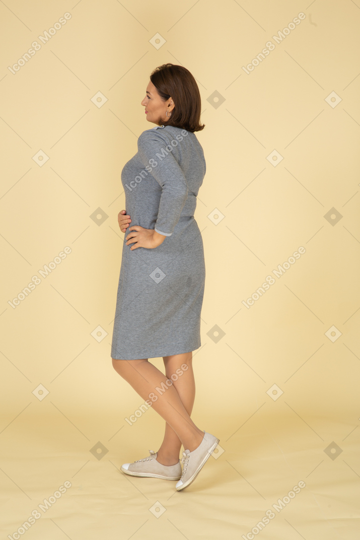 Rear view of a woman in grey dress posing