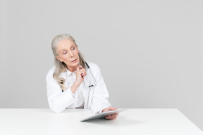 Aged female doctor working on a digital tablet