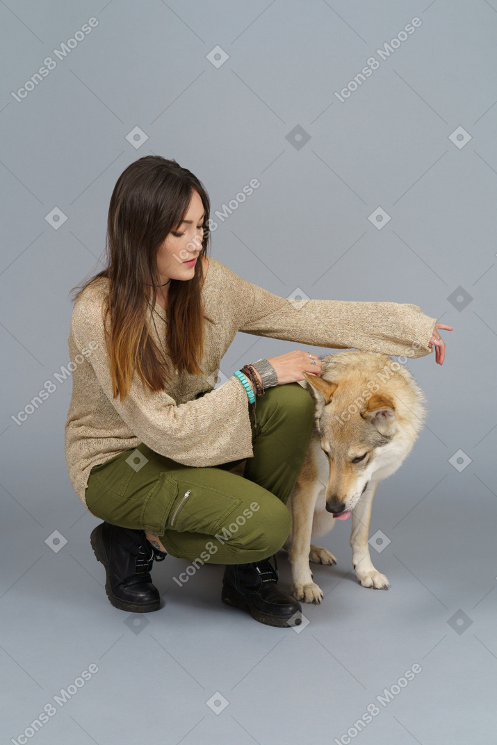 De cuerpo entero de una maestra sentada junto a su perro y mirando hacia abajo