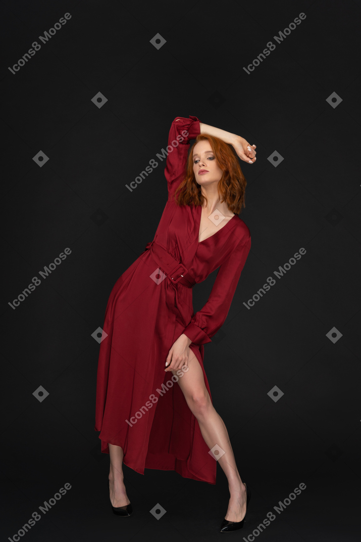 A frontal view of the young beautiful girl dressed in red and posing on the black background