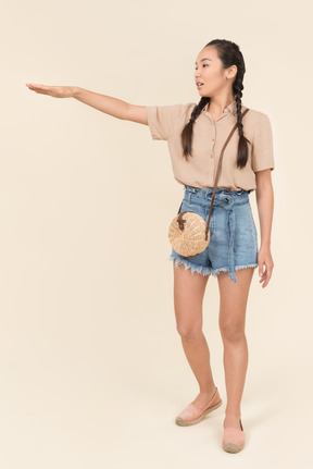 Young woman in casual clothes raising her hand