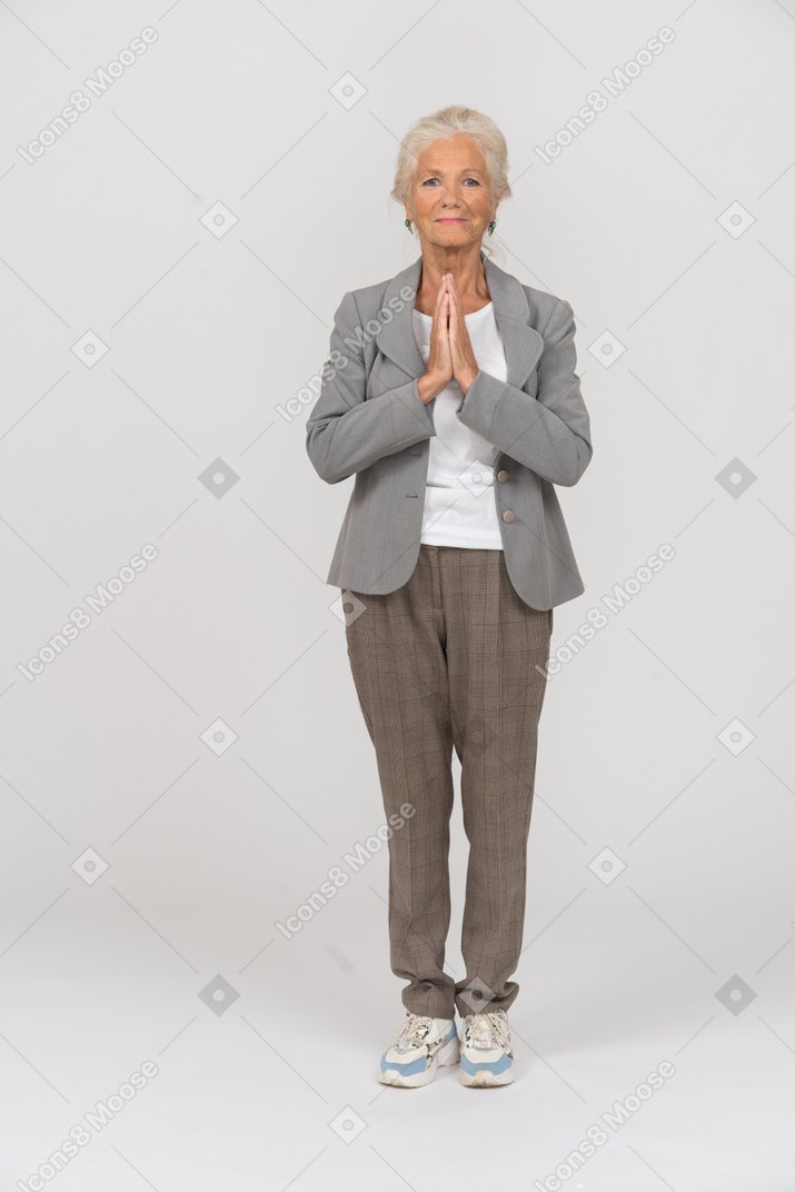 기도하는 몸짓을 하는 양복을 입은 노부인의 전면 모습