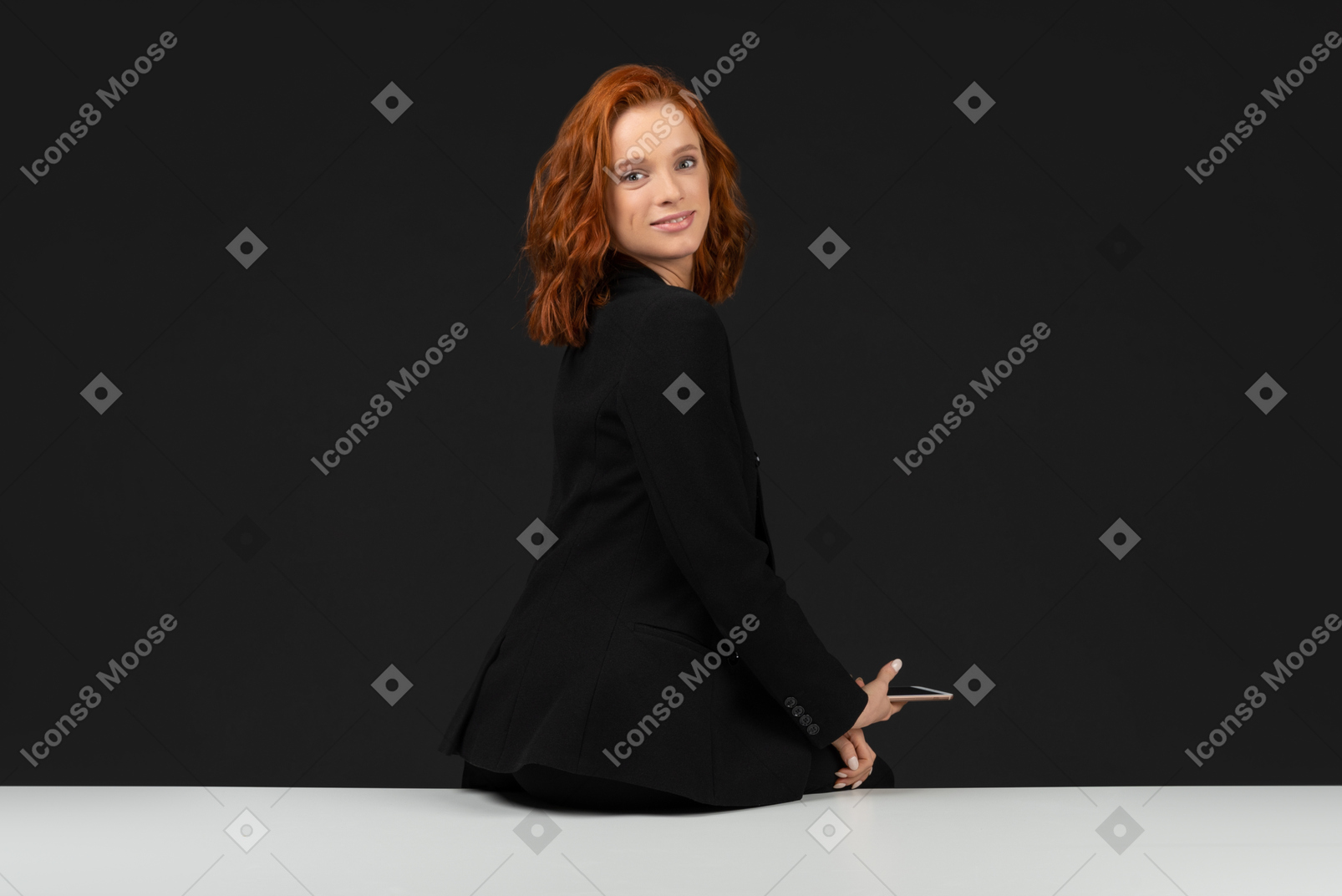 A side view of the young red haired girl holding the phone and looking at the camera