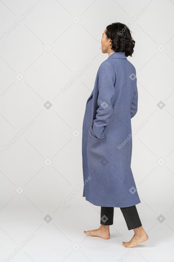 Punto di vista posteriore della donna in cappotto che cammina a piedi nudi
