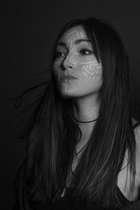 Noir three-quarter portrait of a young female with ethnic facial art