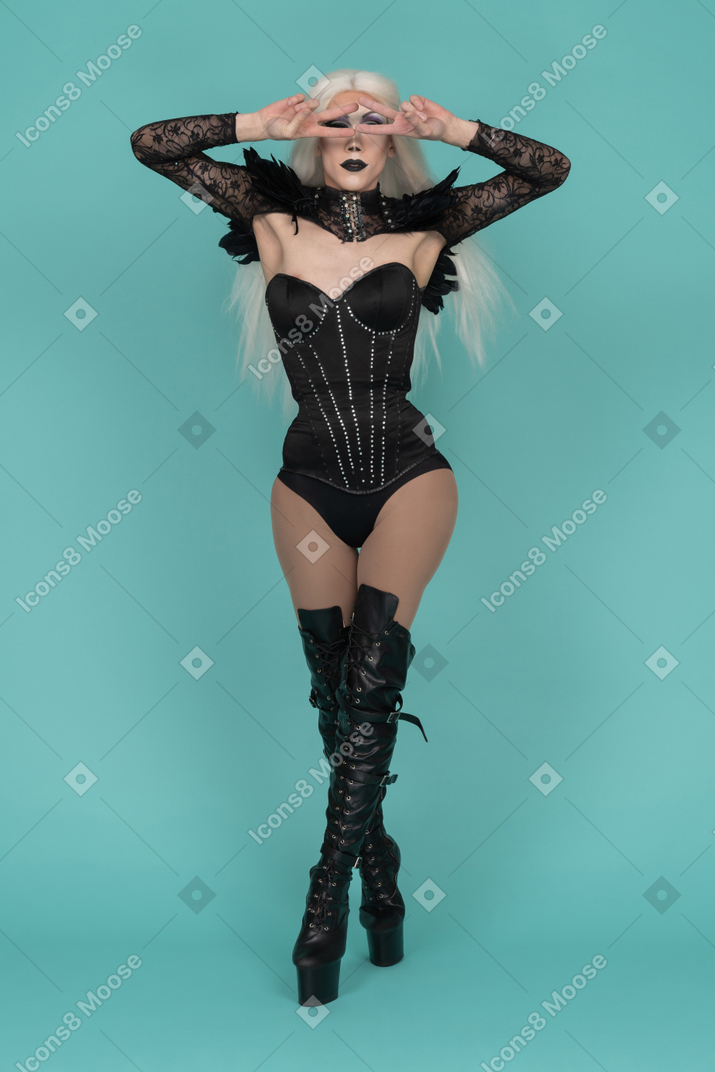 Transvestite posing with two finger on both hands holding near face