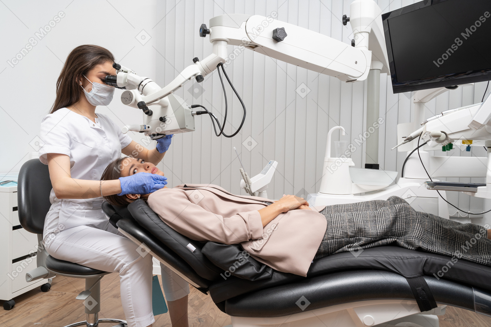 Comprimento total de uma dentista examinando sua paciente e olhando através do microscópio
